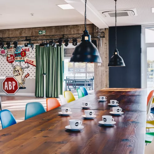 Interior view of eyeo GmbH's Cologne office, featuring the main gathering space in the kitchen with large tables and colorful chairs