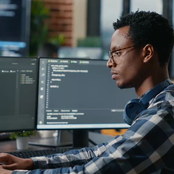 A person sitting down at his desk, engrossed in coding or programming work, portraying a focused and productive workspace